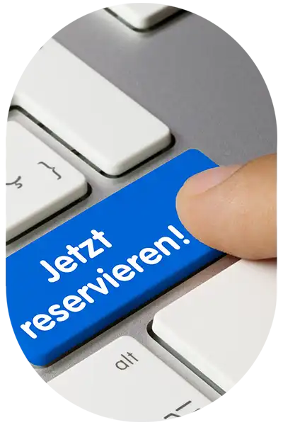 Eine blaue Taste "Jetzt Reservieren" auf einer Tastatur wird gedrückt