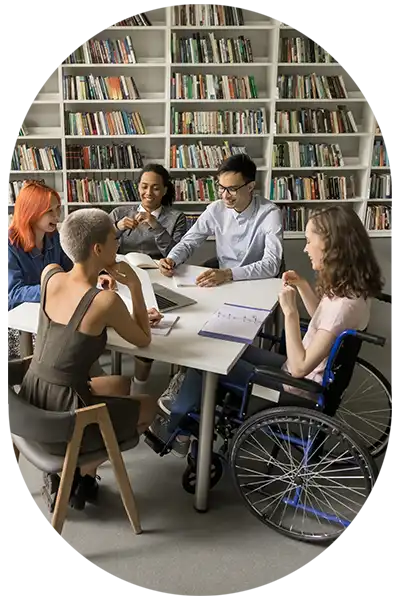 Workshop mit mehreren Personen an einem Tisch, darunter eine Frau im Rollstuhl