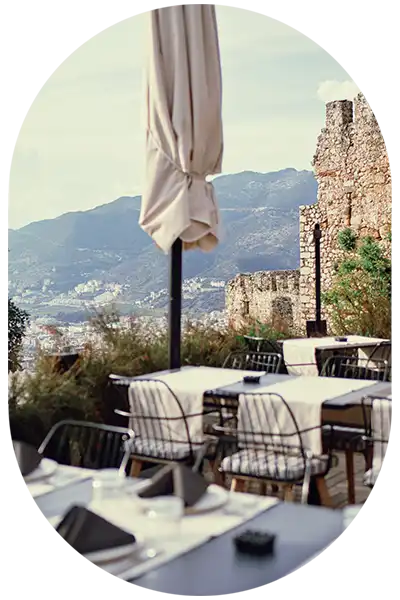 Geschlossene Sonnenschirme stehen auf der Terrasse einer Burg über einem Tal